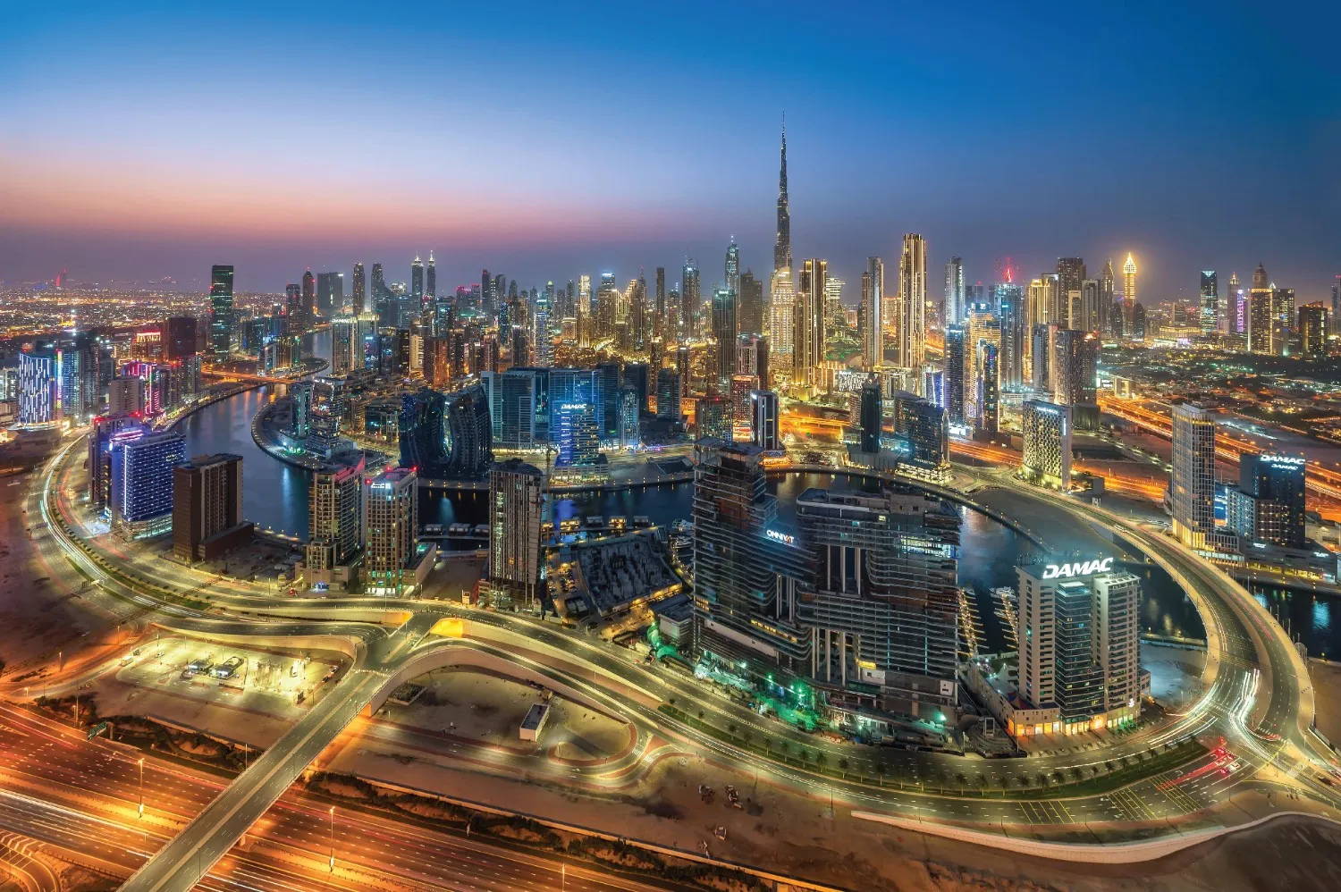 Dubai city skyline with modern buildings and palm trees along a wide street in daylight